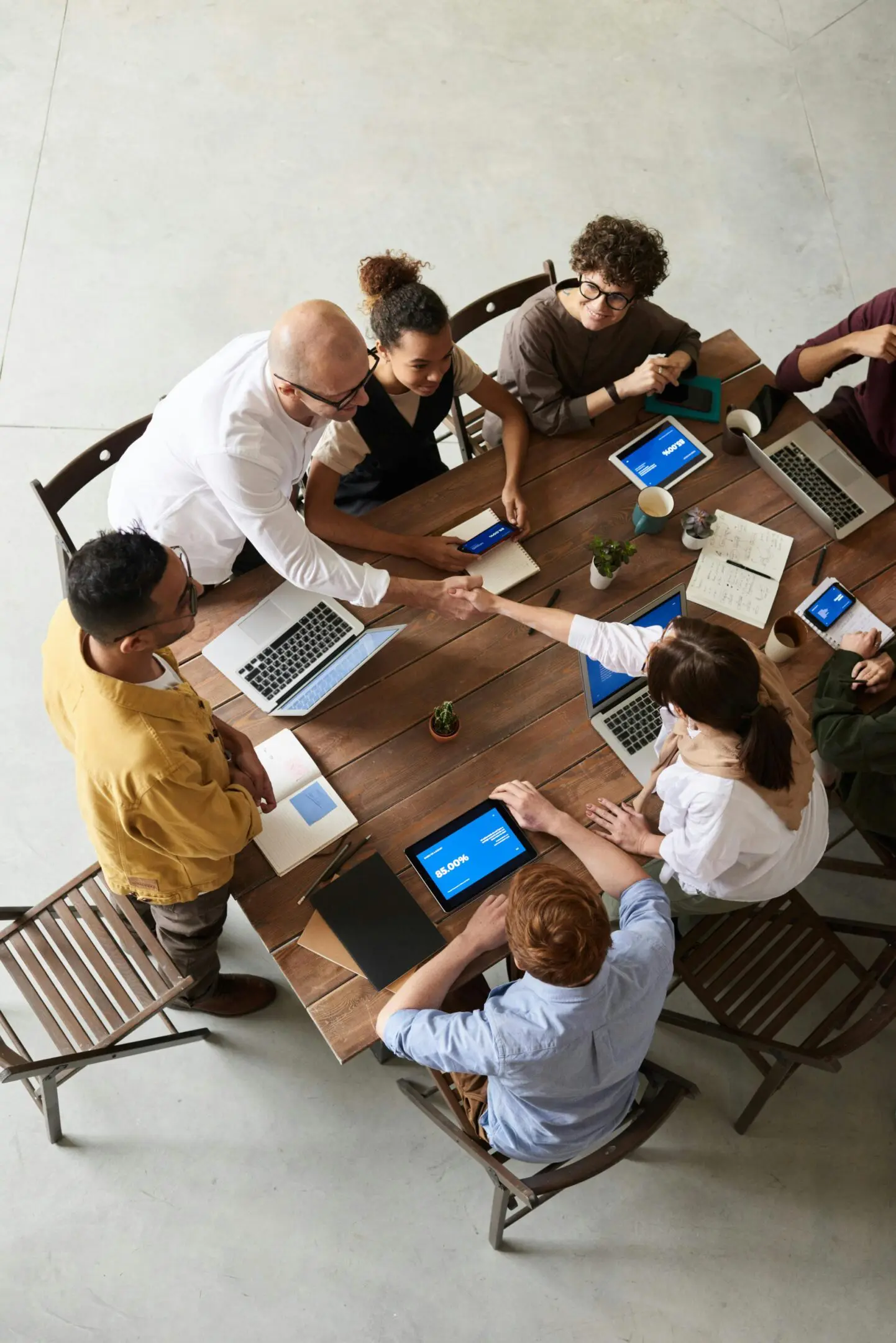 A team collaborates around a table with laptops and tablets.