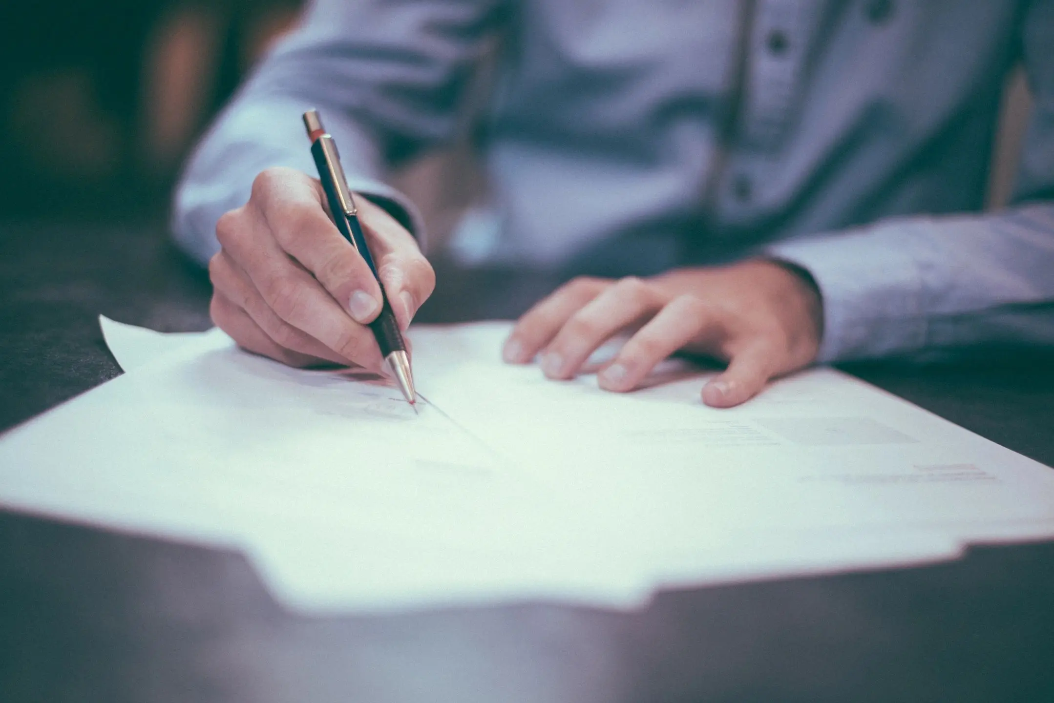 Person signing a document with a pen.