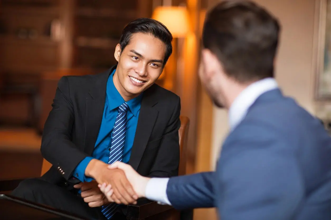 Two men shaking hands during a business meeting, smiling and making a connection.