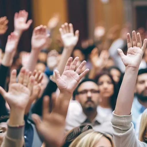 A crowd with many hands raised in a meeting or event.