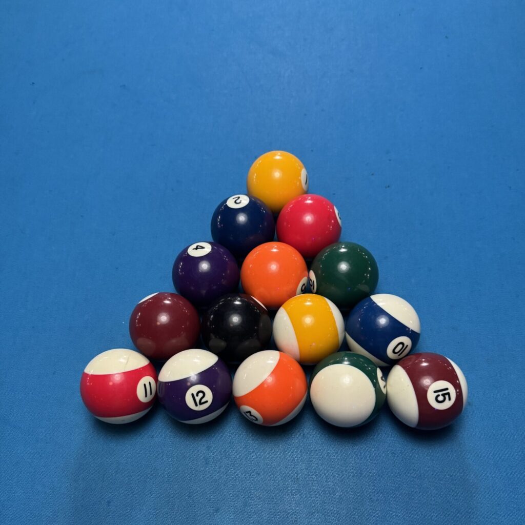 A pyramid of colorful billiard balls on a blue felt pool table.