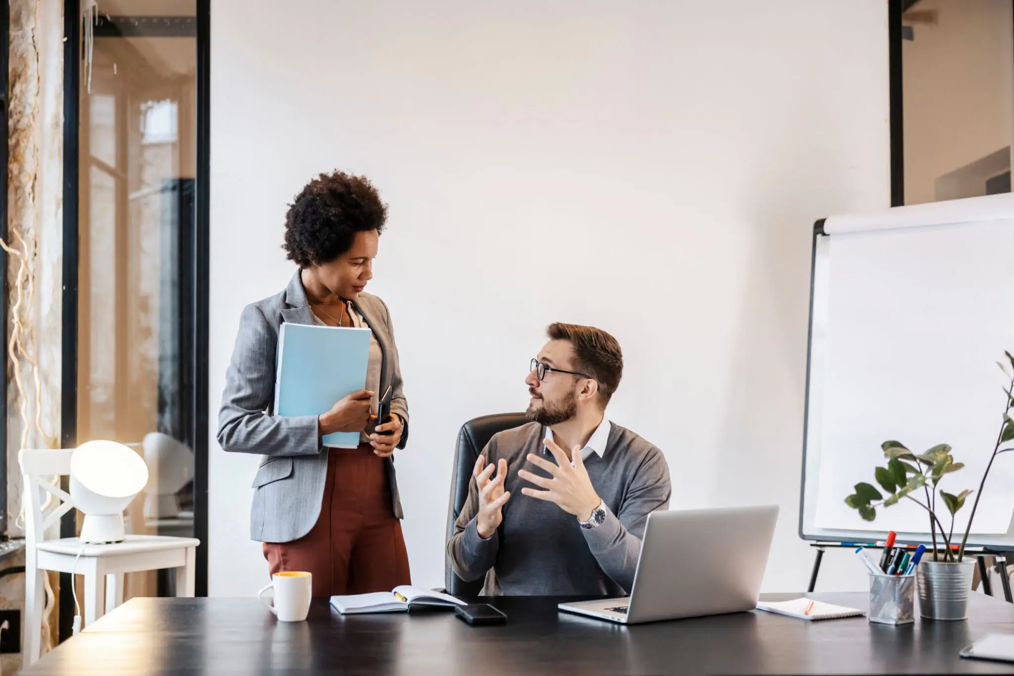 Two colleagues discussing work in an office setting.